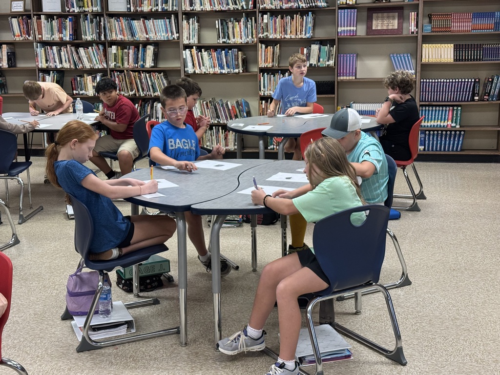 students in a library at a table working on a project