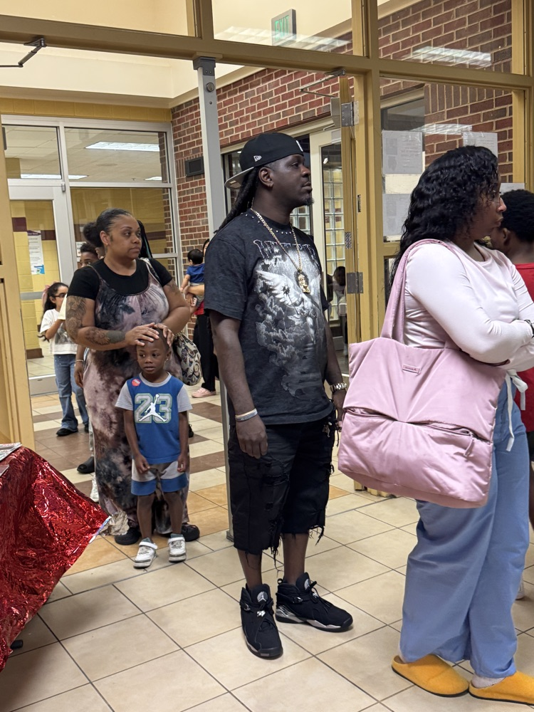 parents and students standing in line in the lunchroom of a school