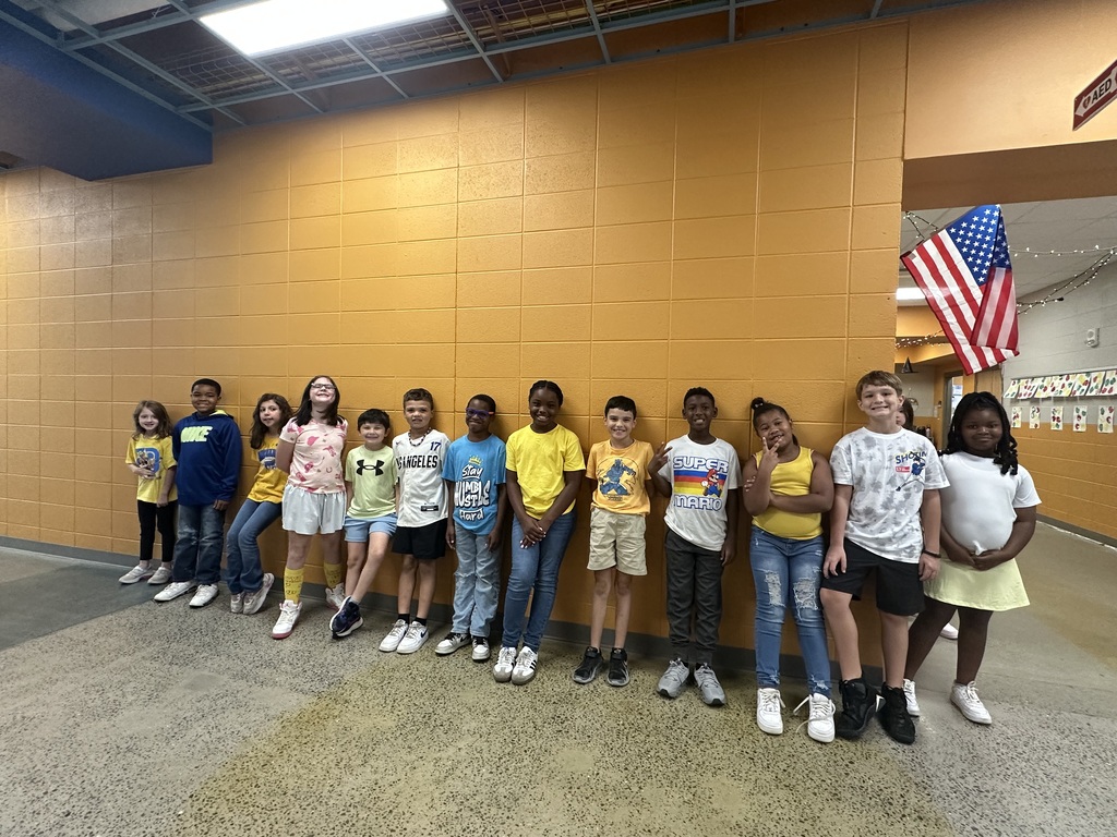 Students posing with class outside in the hallway showing their gold color clothing.