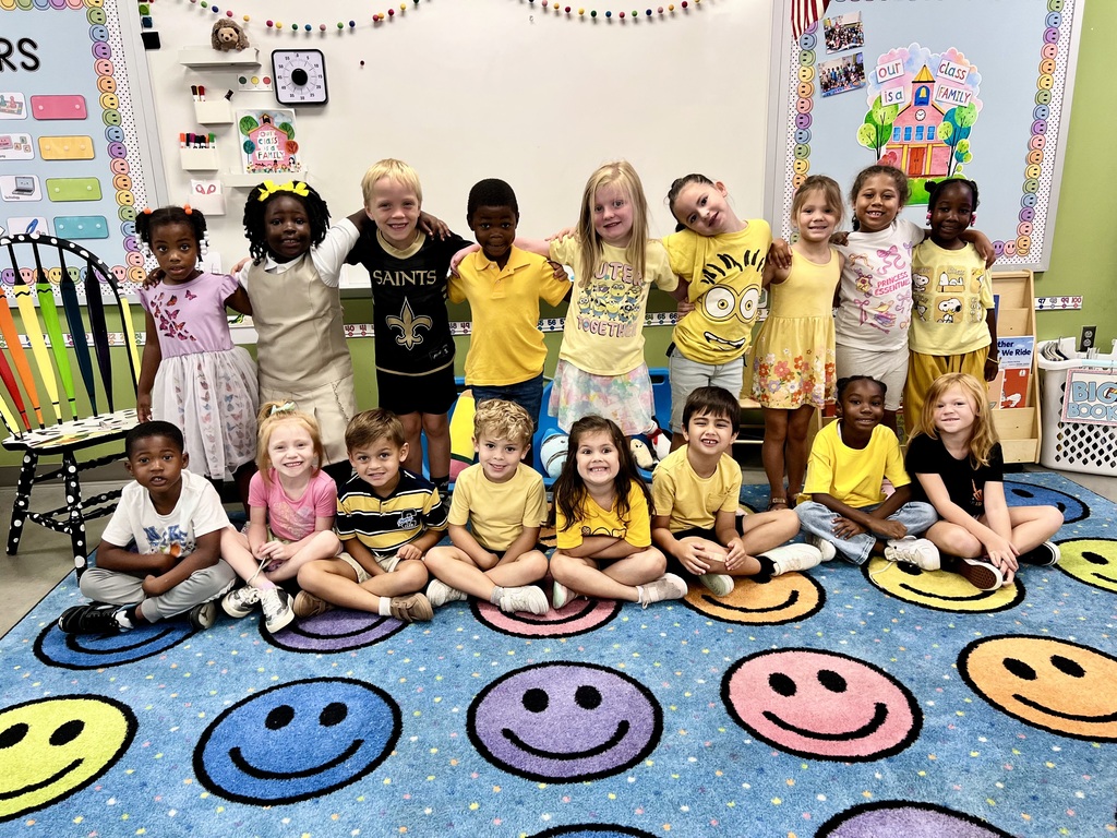 Students posing on the rug in their classroom showing their gold clothing