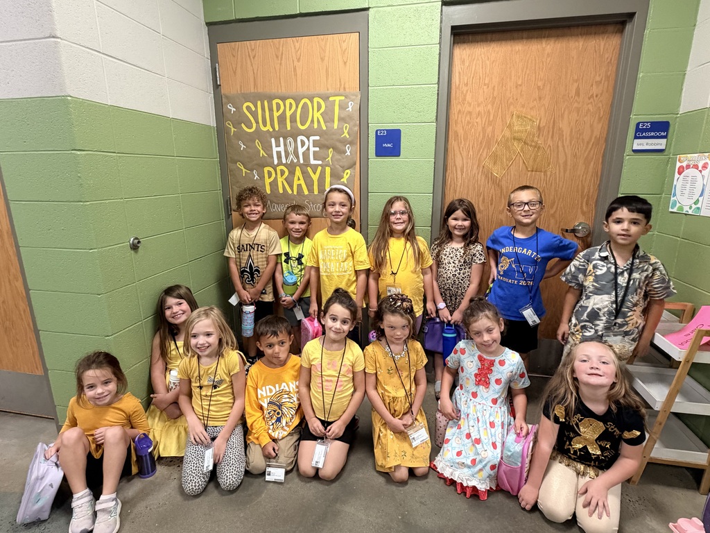 Students posing with class outside in the hallway showing their gold color clothing.