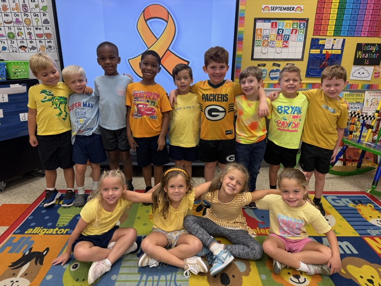 Kindergarteners in gold posing with their arms around each other