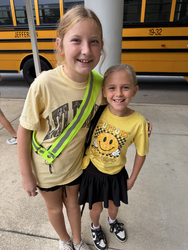 Two students smiling in gold shirts