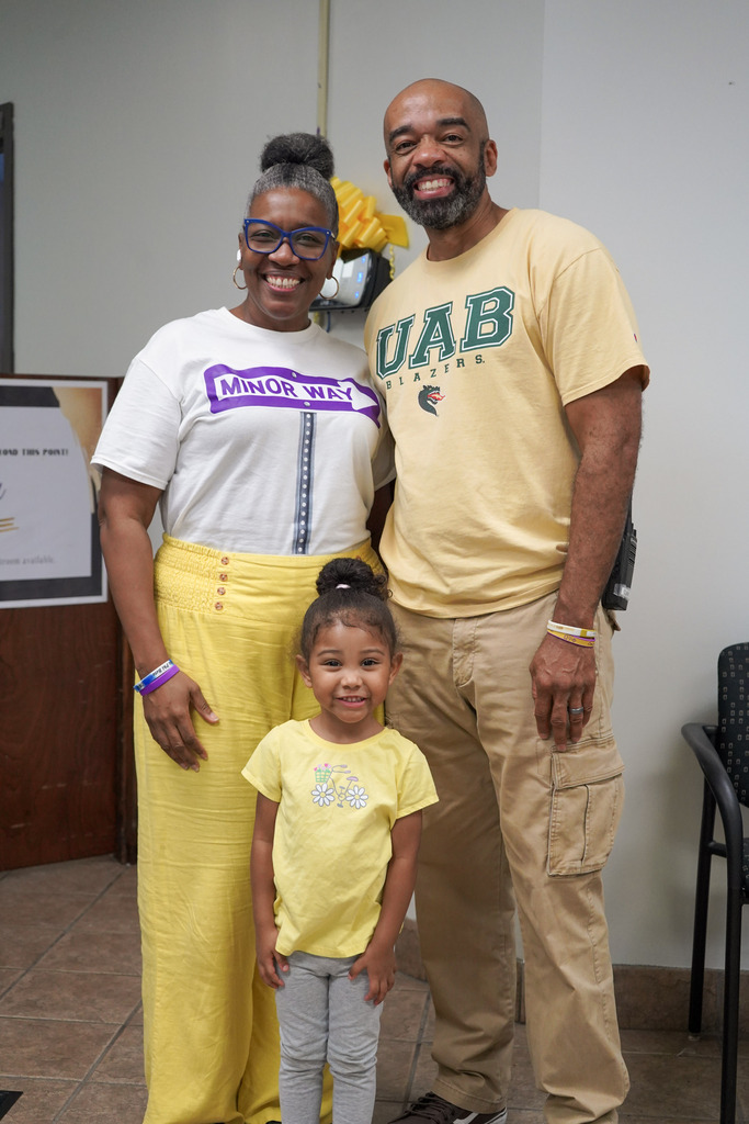 A man, woman, and child smile for a photo while standing inside a school.