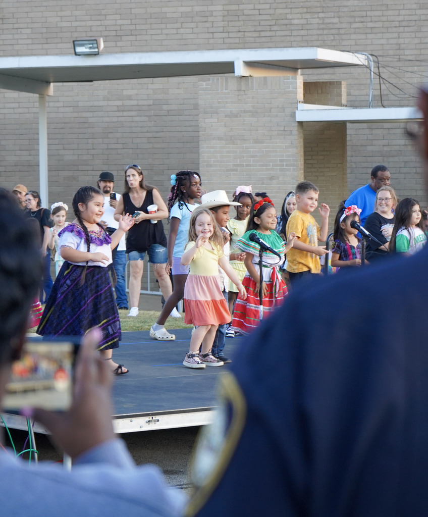 Children perform a dance routine on a stage.