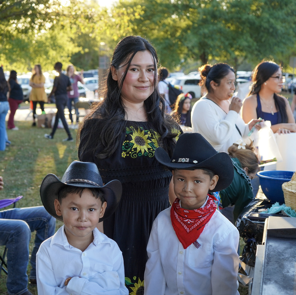 A woman and two children smile for a photo while standing outdoors.