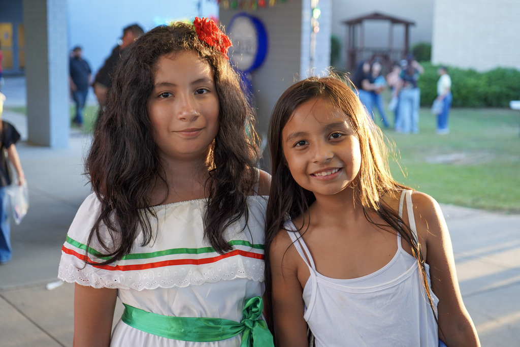 Children smile for a photo while standing outdoors.