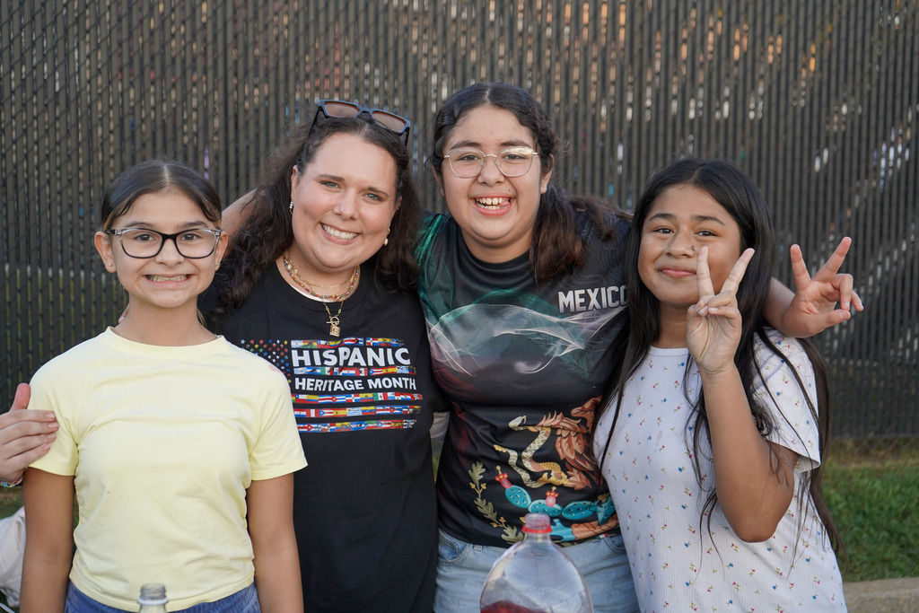 Students and a teacher pose for a photo while standing outdoors.