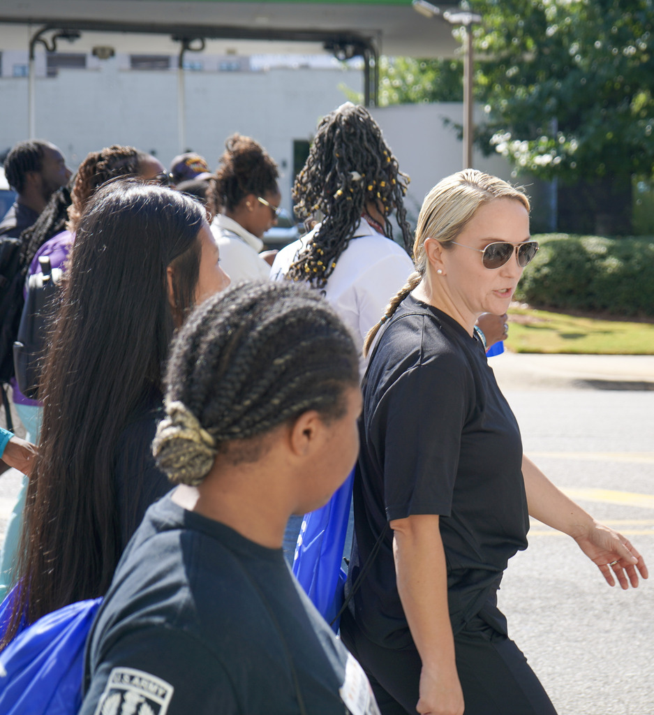 Community members and students walk down a street wearing weighted backpacks to honor veterans lost to suicide.