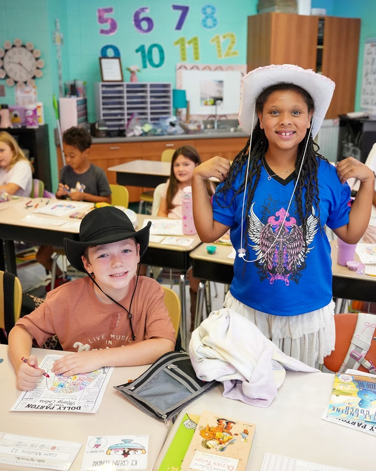 Two students pose for a picture on 9/25 Dolly Parton Day. They are wearing cowboy hats and smiling.