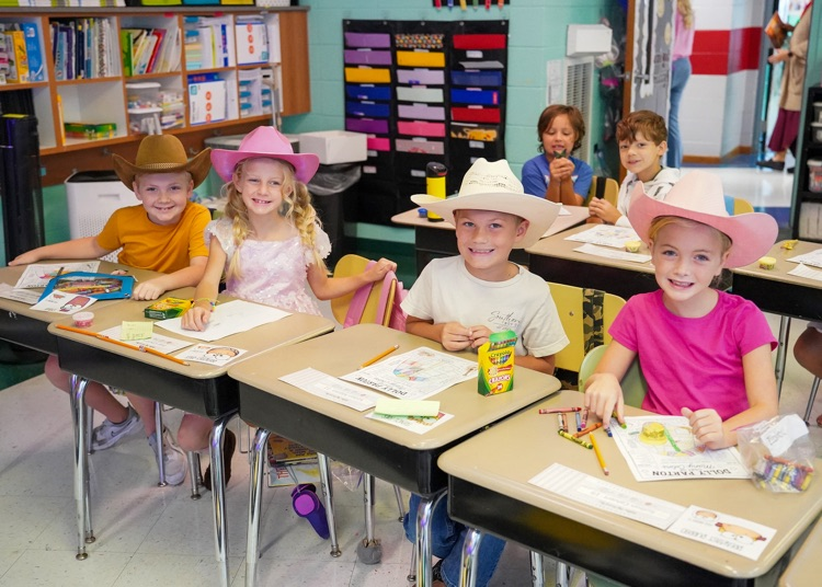 Four elementary age students wear cowboy hats on Dolly Day at Snow Rogers Elementary.