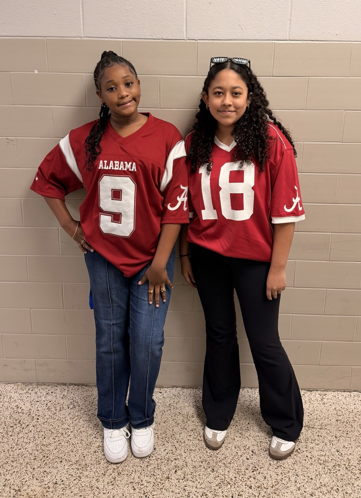 Two HMS students pose together wearing crimson Alabama football jerseys.