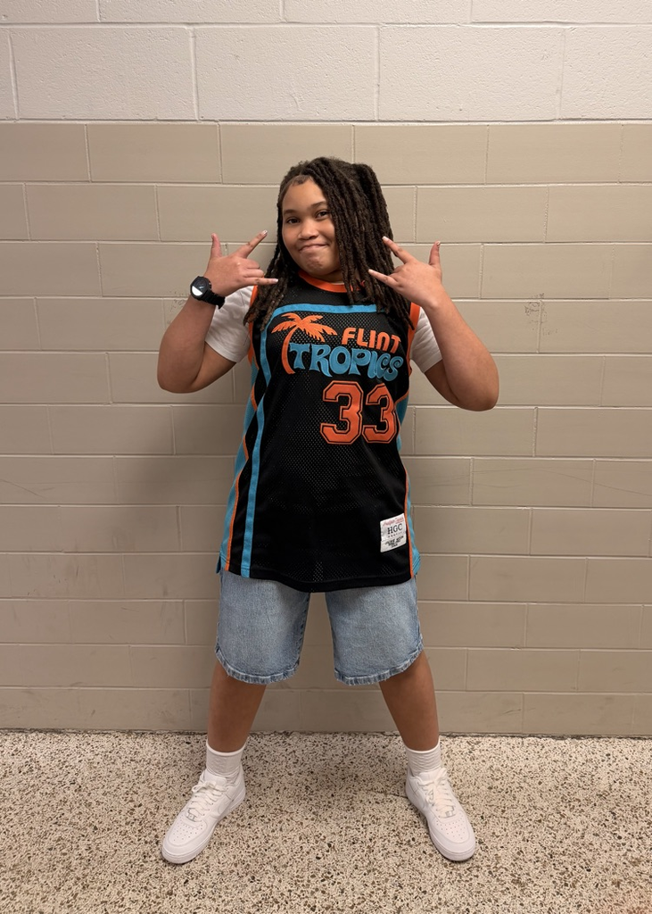 HMS student poses in a black, orange, and teal Flint Tropics number 33 jersey.