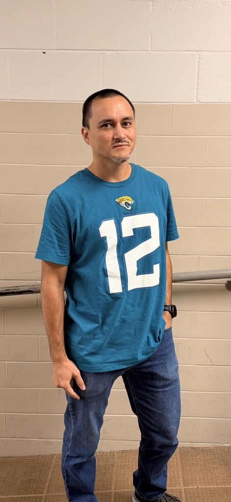 HMS staff member poses in a teal Jacksonville Jaguars number 12 shirt.