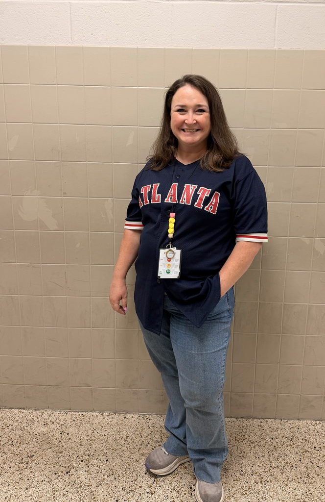 HMS staff member smiles while wearing a navy Atlanta sports jersey.