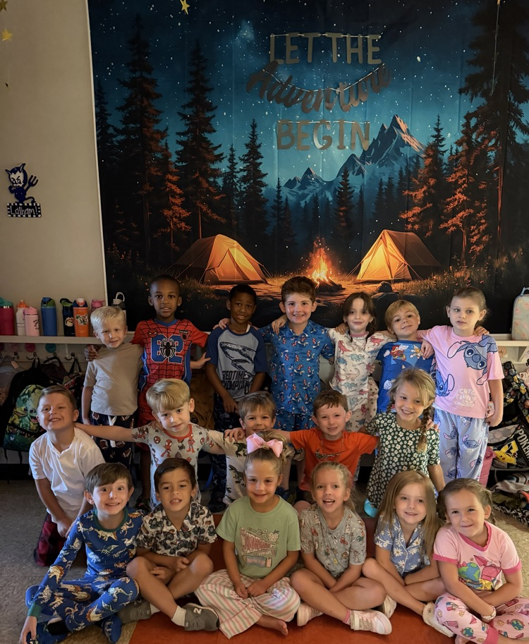 Kindergarten students with their arms around each other in front of a camping backdrop