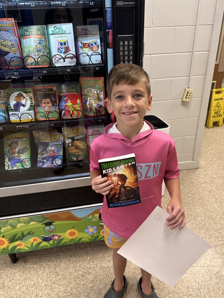 3rd grade boy smiling and holding a book