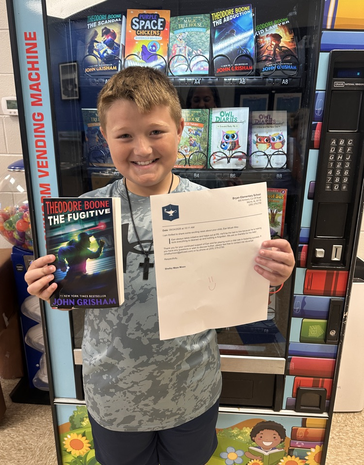 5th grade boy holding book and letter and smiling