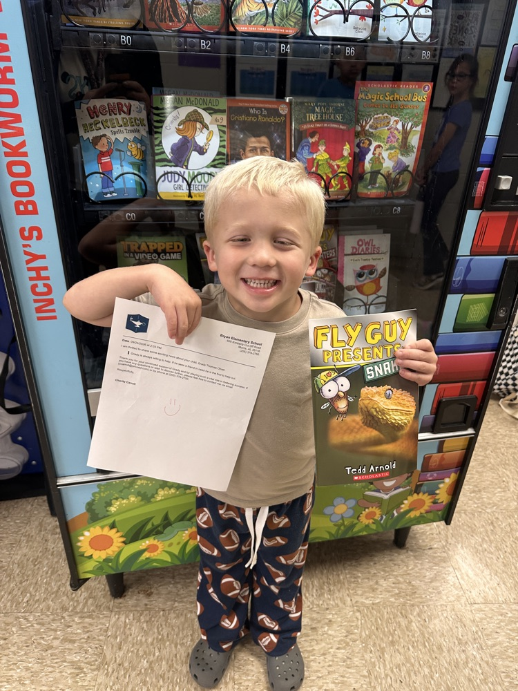 Kindergarten boy smiling holding a book and a letter