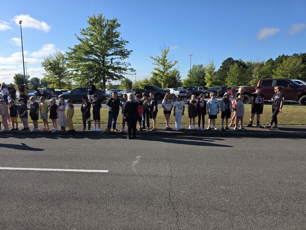 students standing on the sidewalk waiting for the parade to start