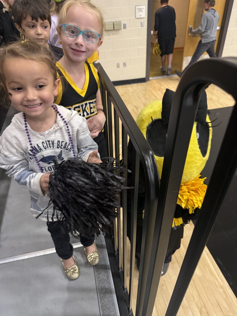 3 students standing by a yellow jacket mascot