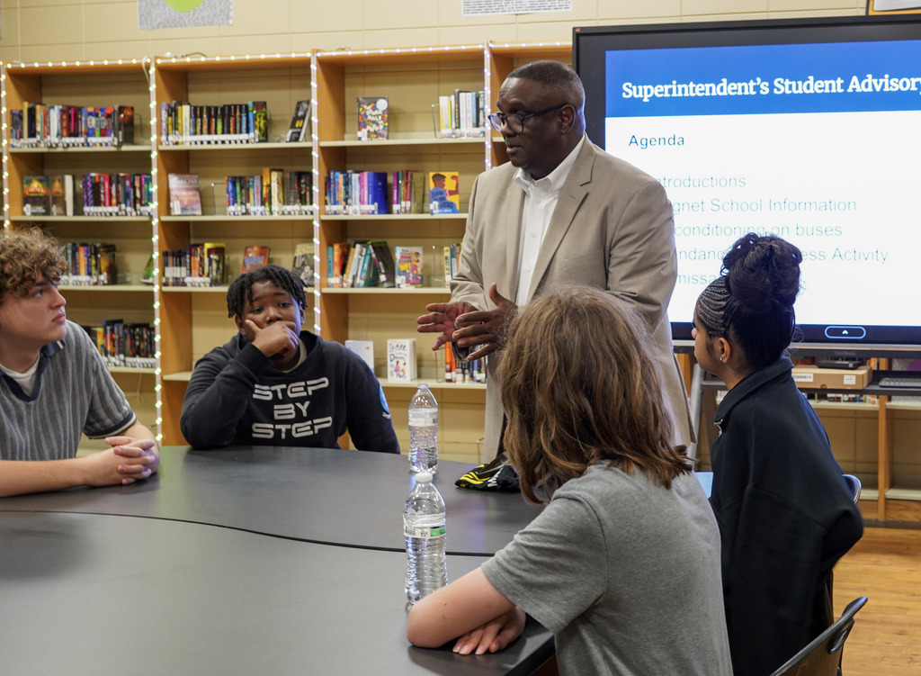 JEFCOED Superintendent Dr. Walter Gonsoulin speaks to students as they sit at a table in a library.