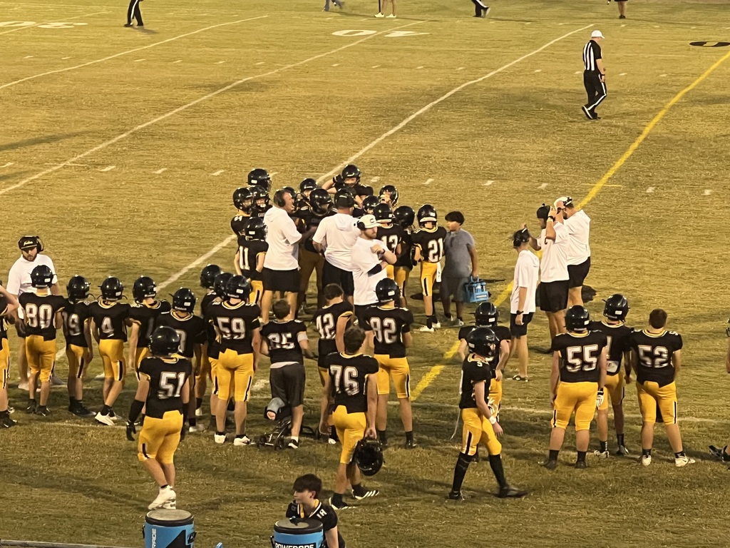 Football players gathered on a field in black and yellow uniforms