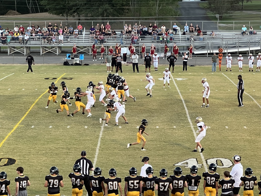 Football players gathered on a field in black and yellow uniforms