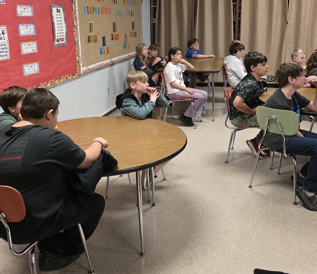 group of students sitting in chairs listening to a guest speaker