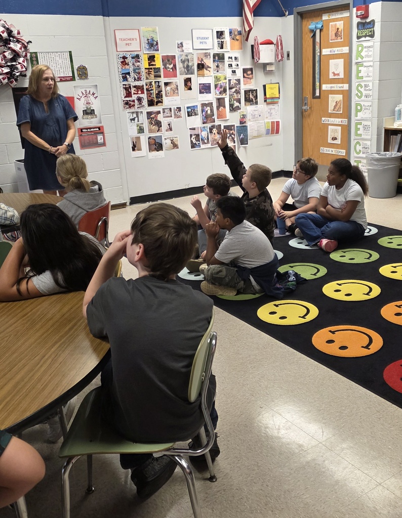 students sitting on the floor listening to a guest speaker