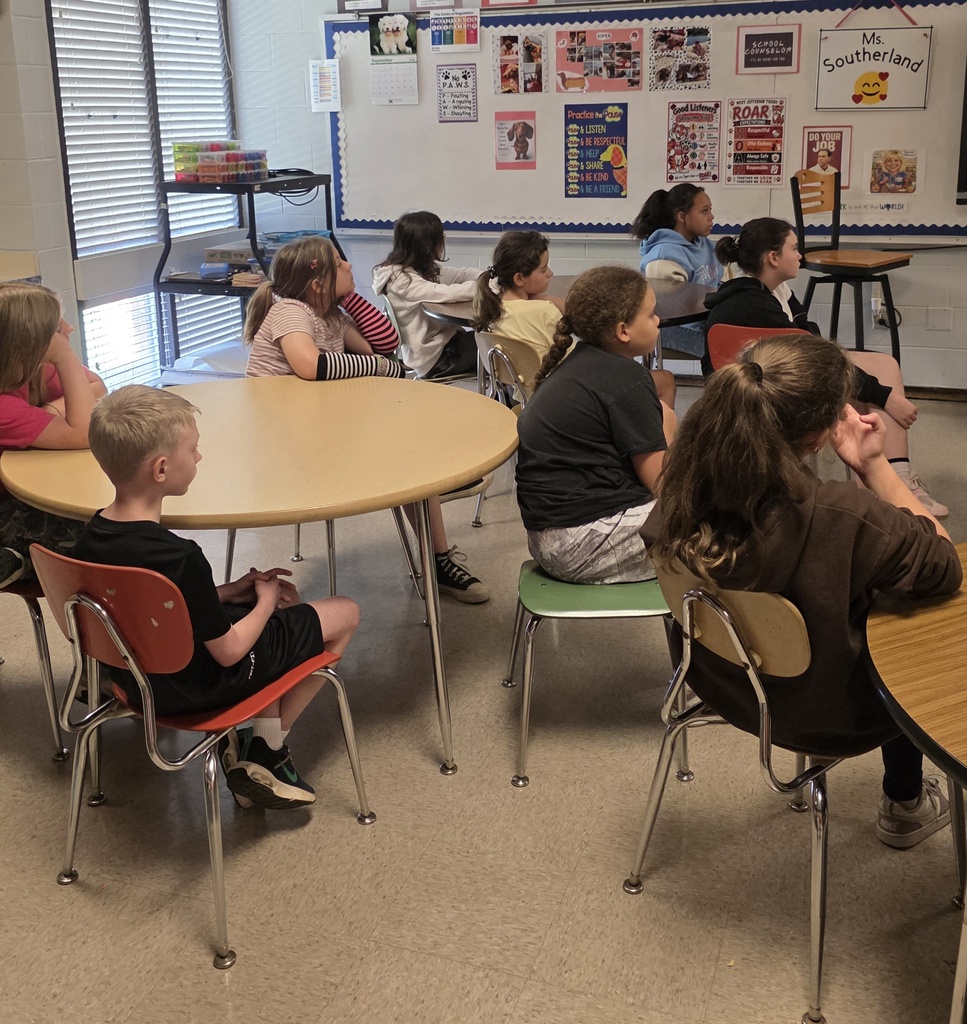 group of students sitting in chairs listening to a guest speaker