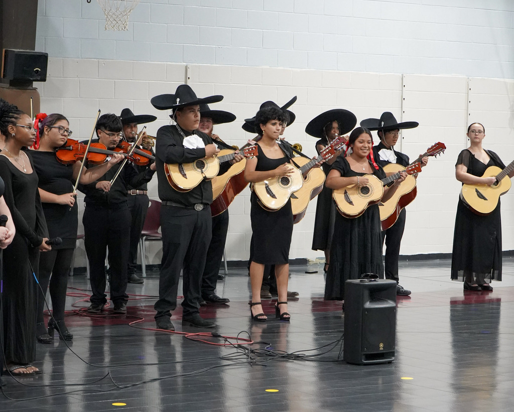 A mariachi band performs inside a school gym.