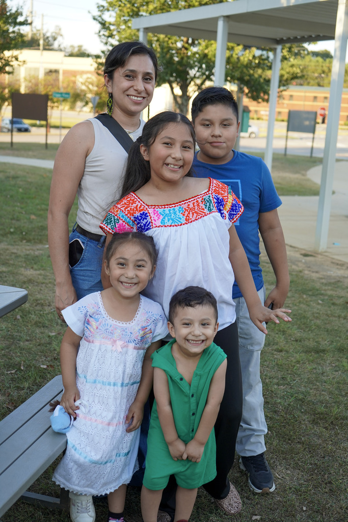 A family stands together and smiles for a photo outdoors.