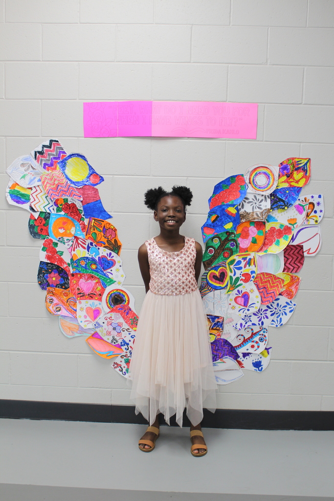 A student in the middle of a mural with wings on either side of her