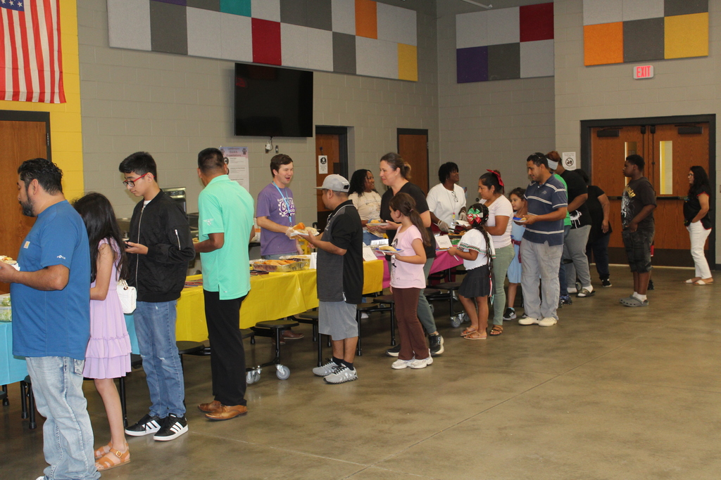 Students and families in line to get food from the potluck