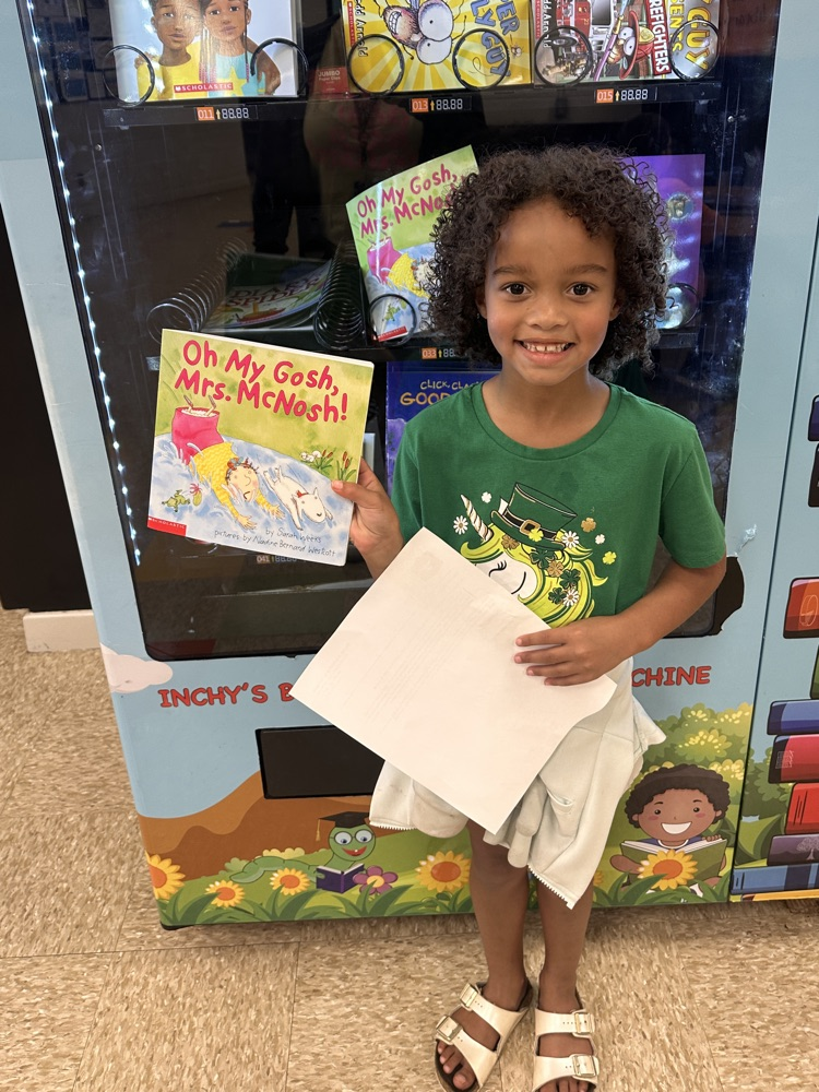 student holding a book prize with a smile