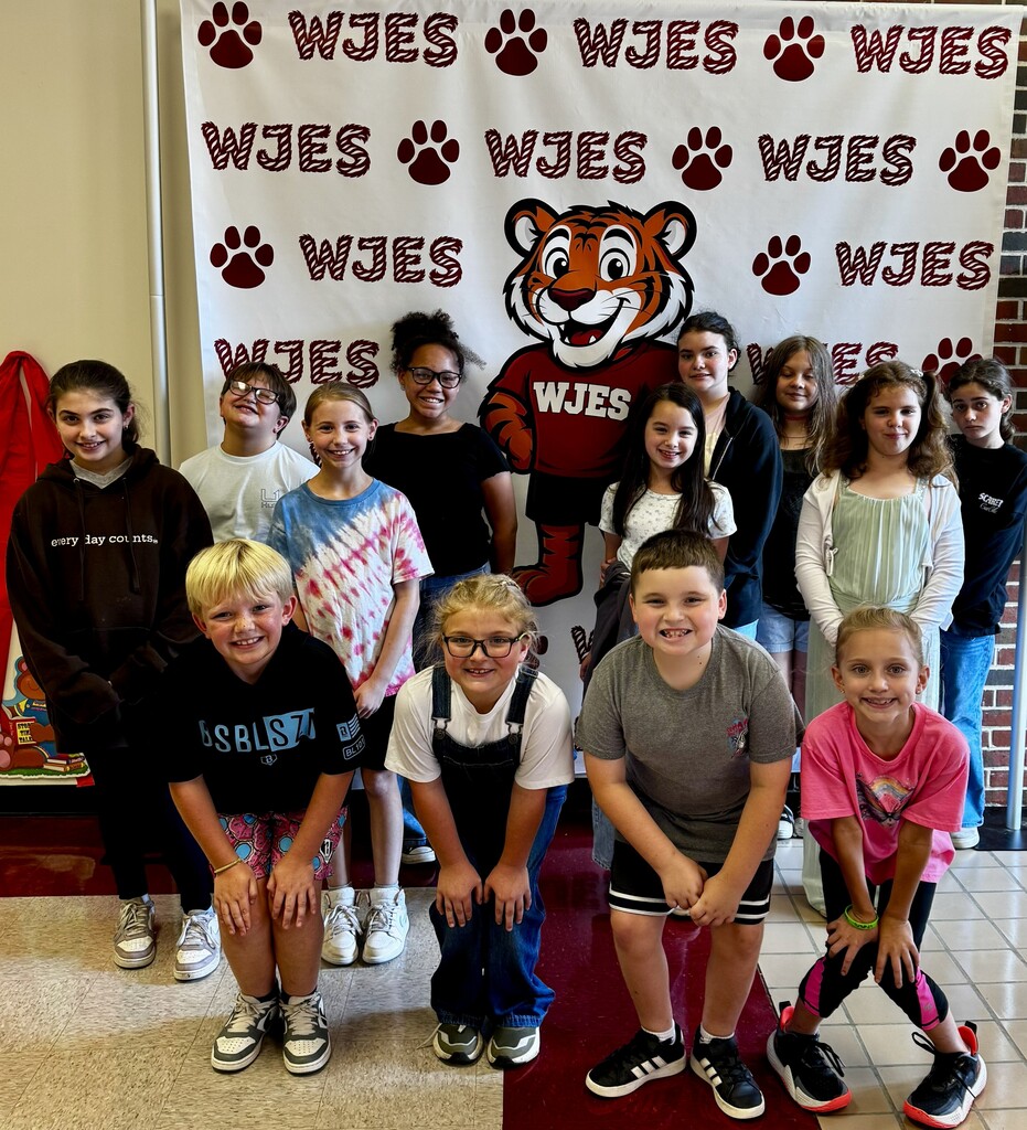 group of students standing in front of the WJES banner