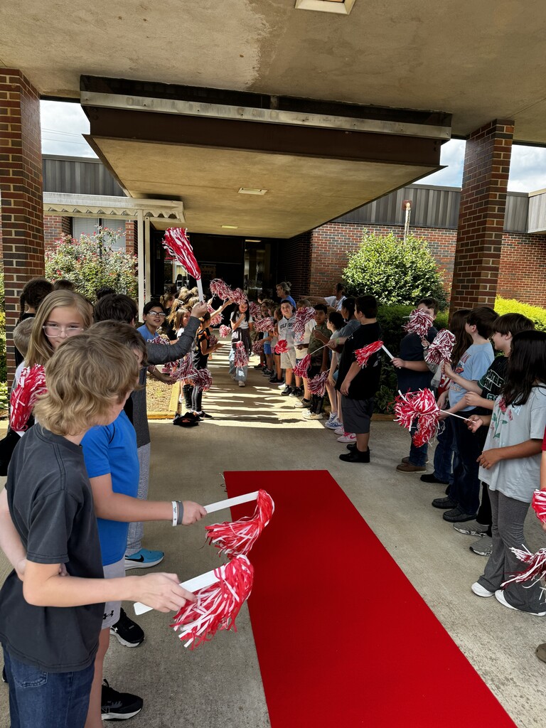students standing on either side of a red carpet shaking shakers