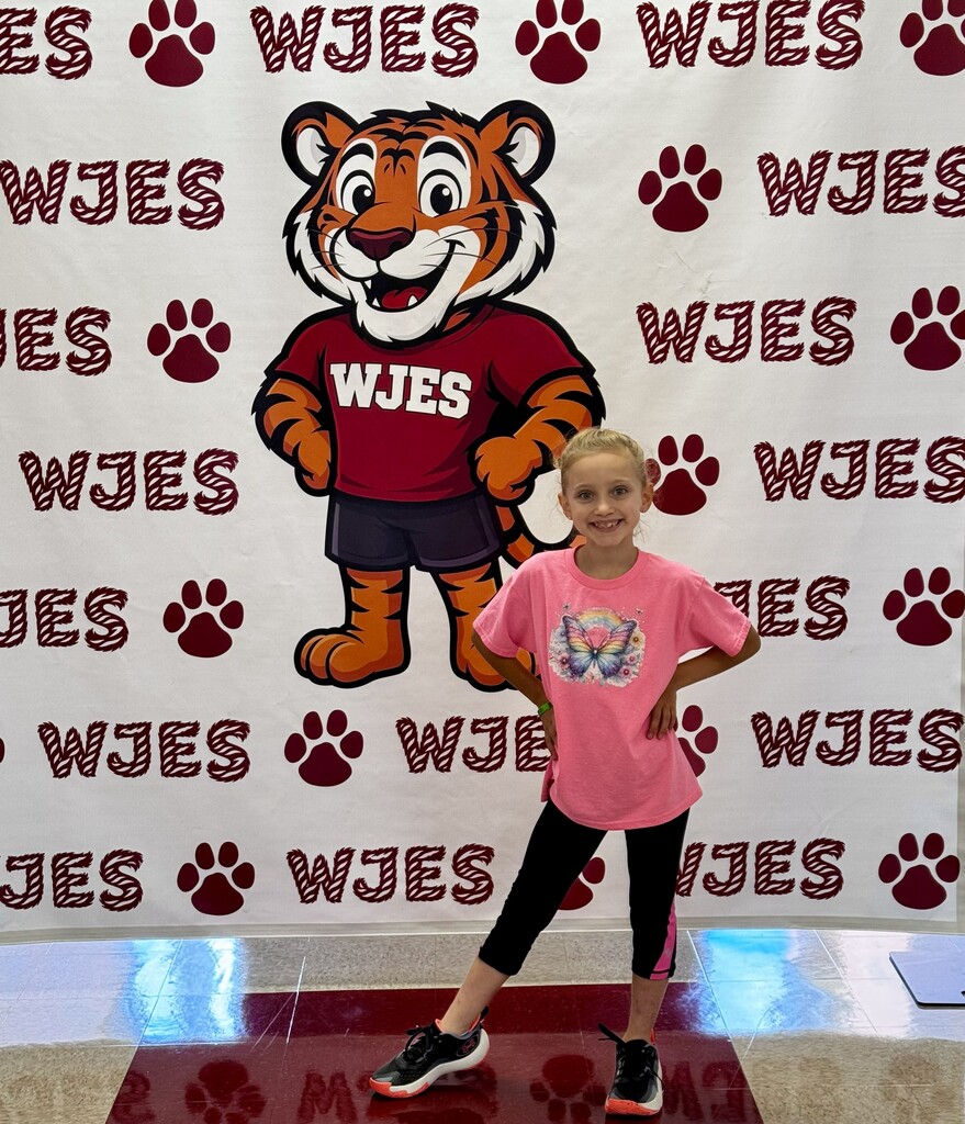 girl standing in front of WJES banner