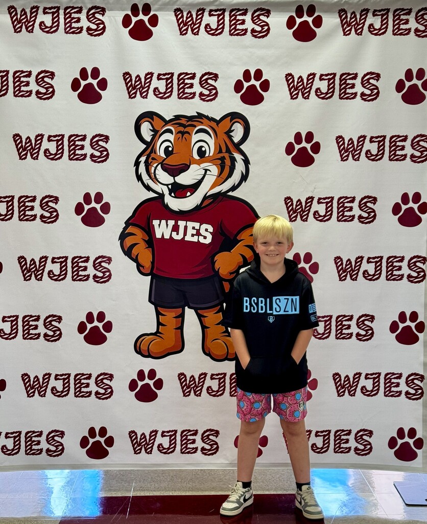 boy standing in front of WJES banner