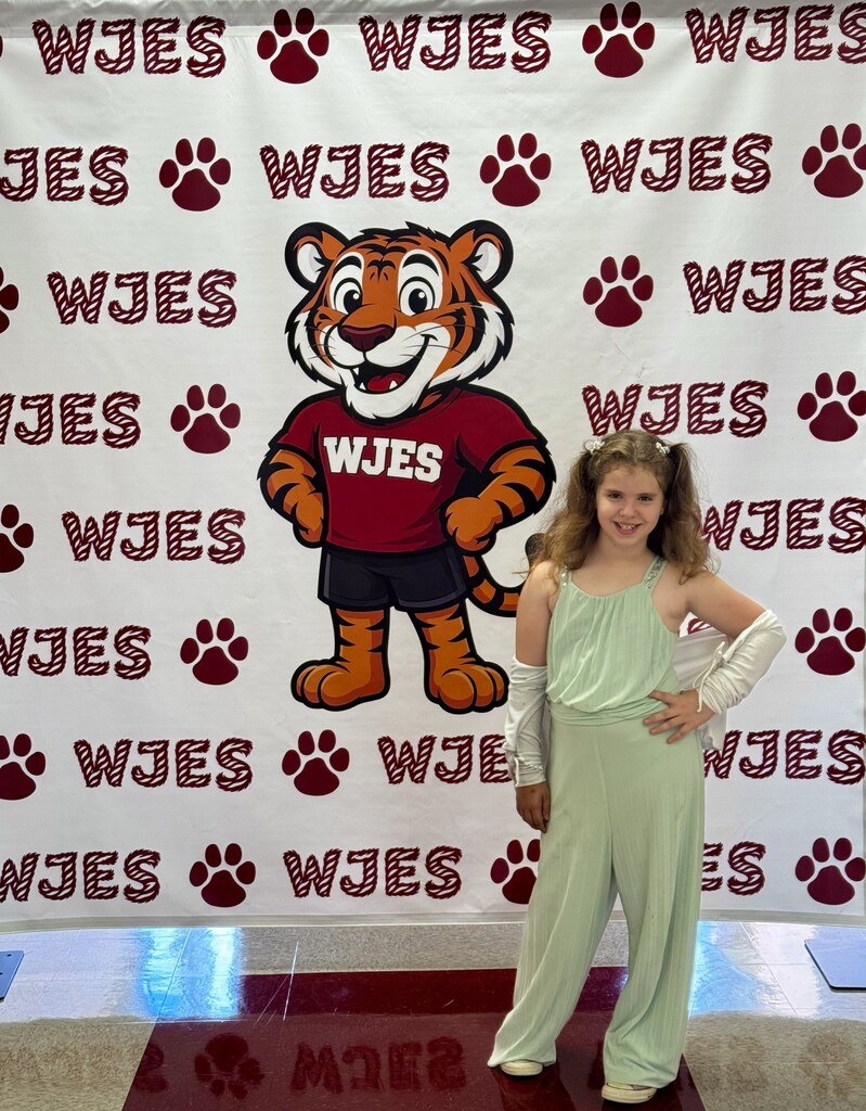 girl standing in front of WJES banner