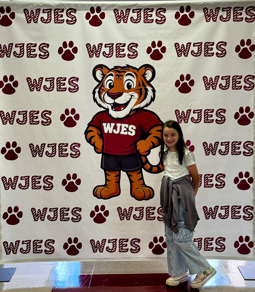 girl standing in front of WJES banner