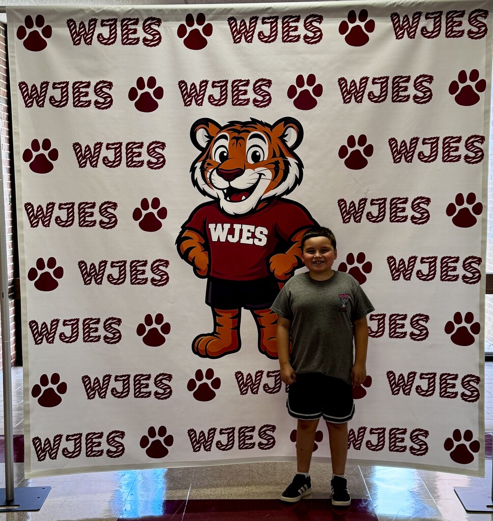boy standing in front of WJES banner
