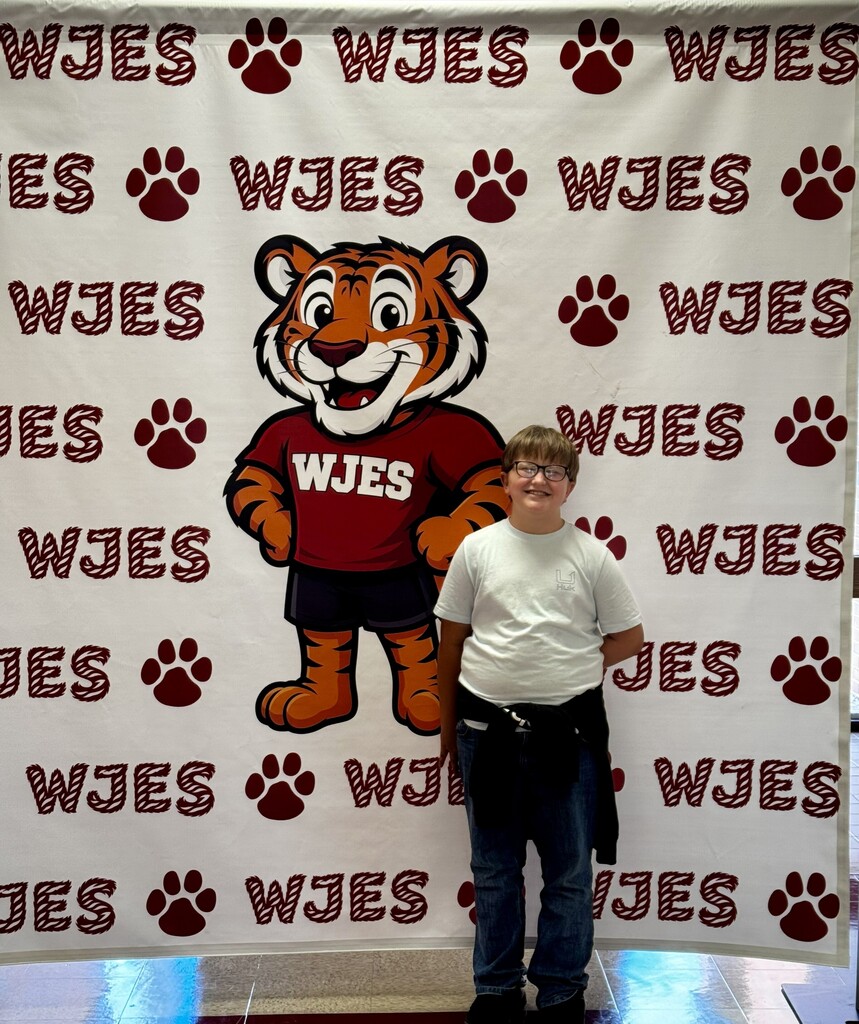 boy standing in front of WJES banner