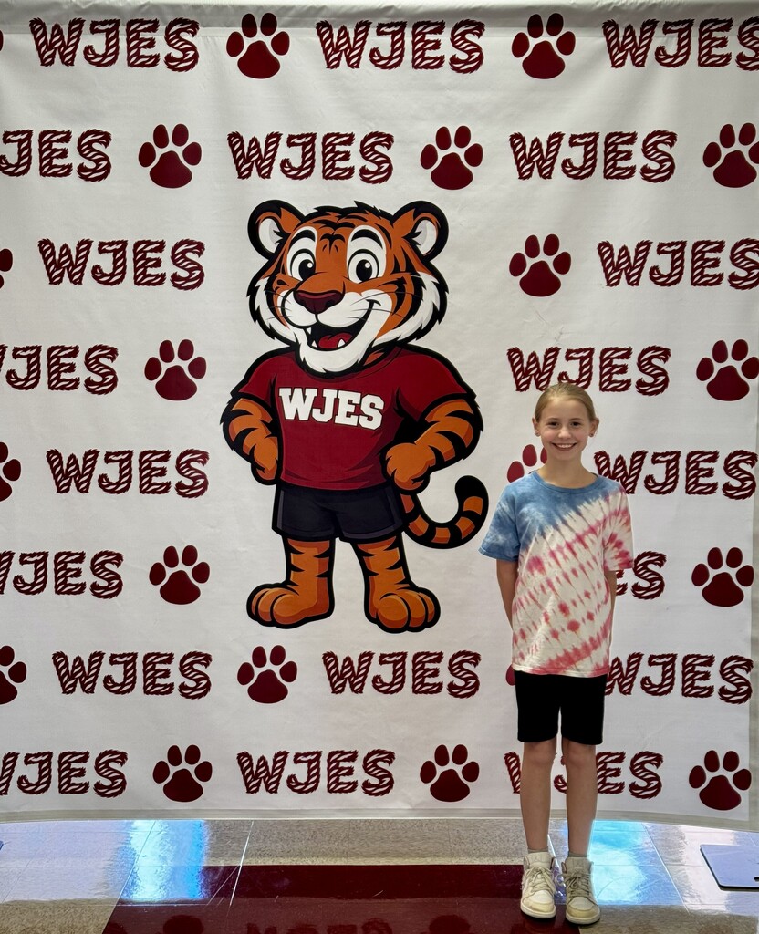 girl standing in front of WJES banner