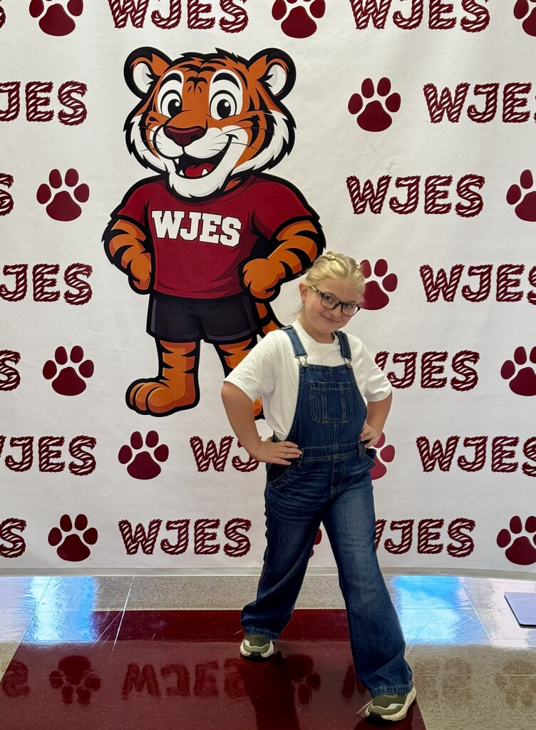 girl standing in front of WJES banner