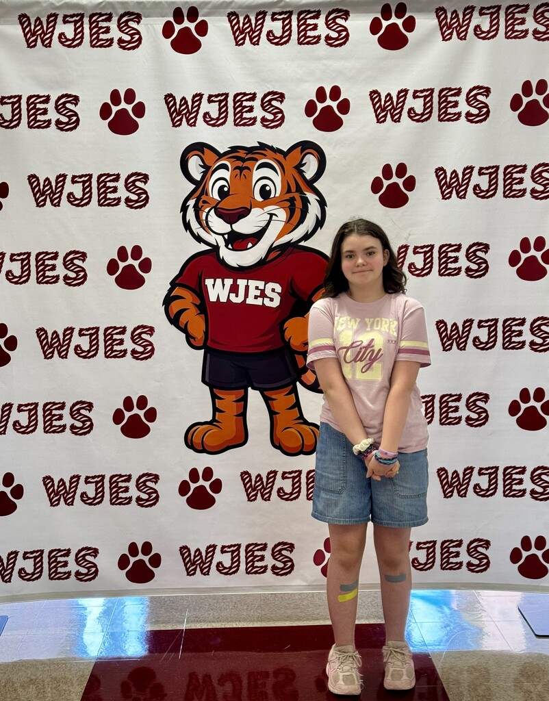 girl standing in front of WJES banner