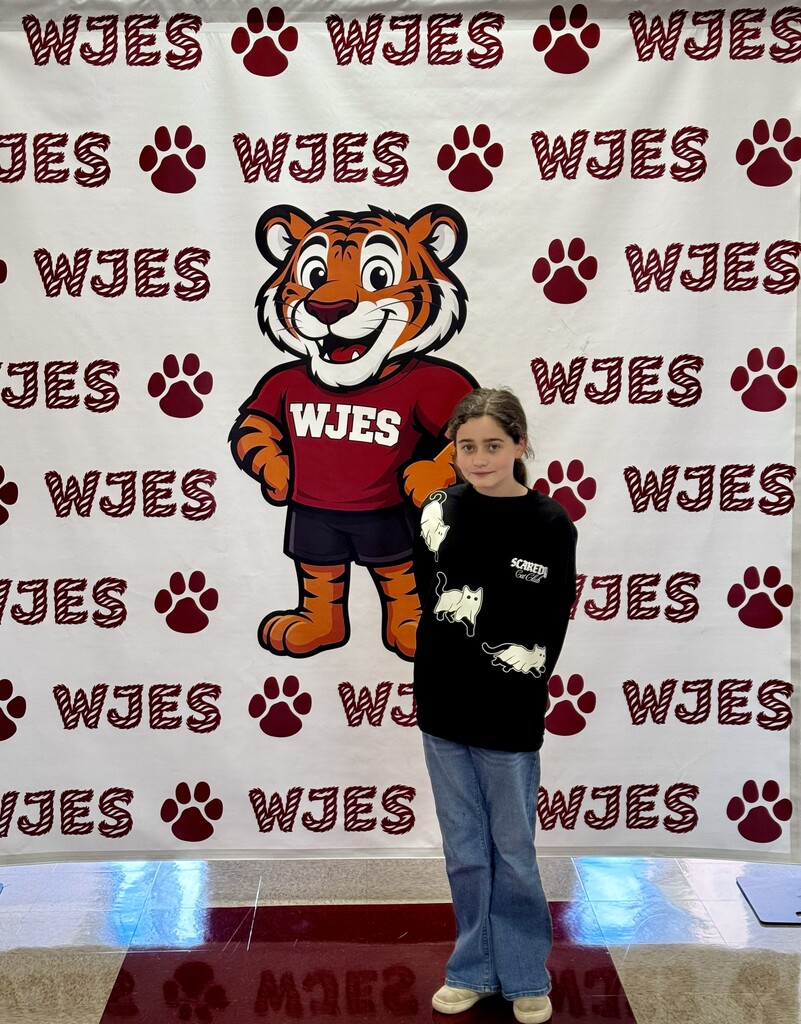 girl standing in front of WJES banner