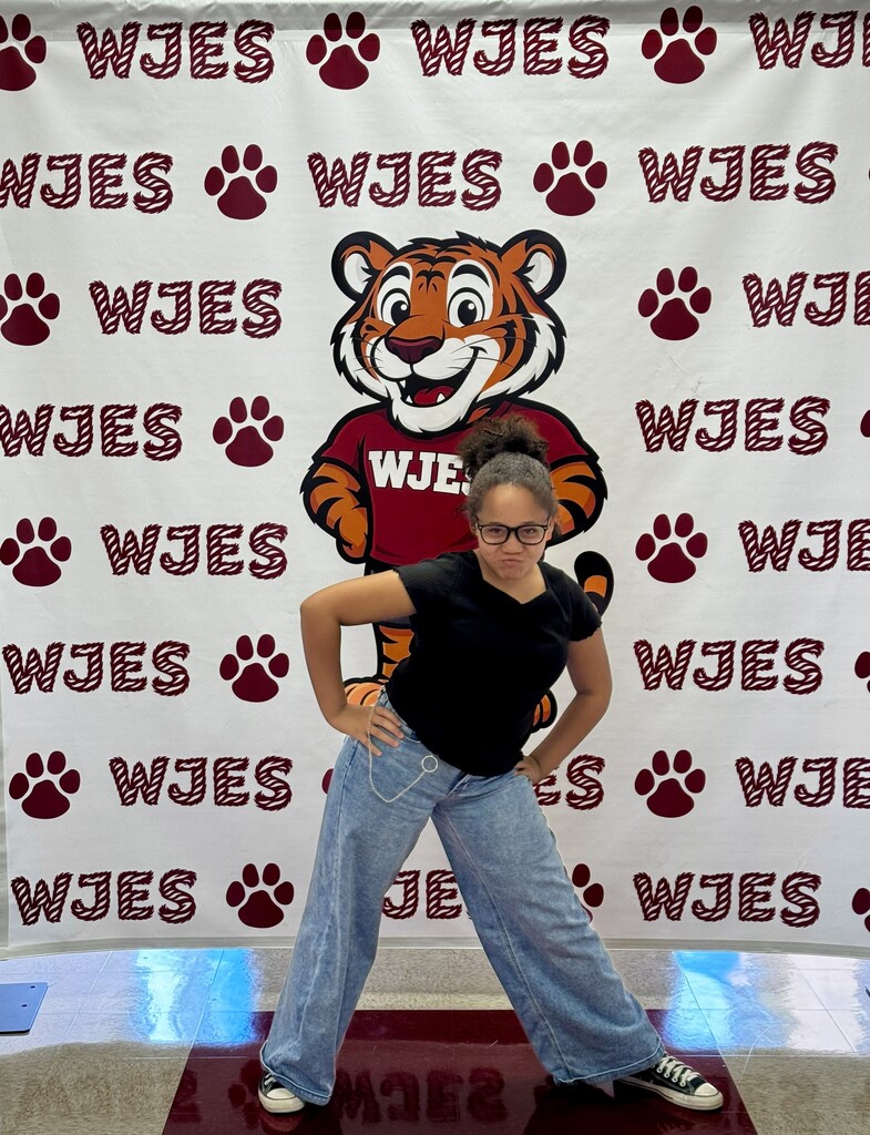 girl standing in front of WJES banner
