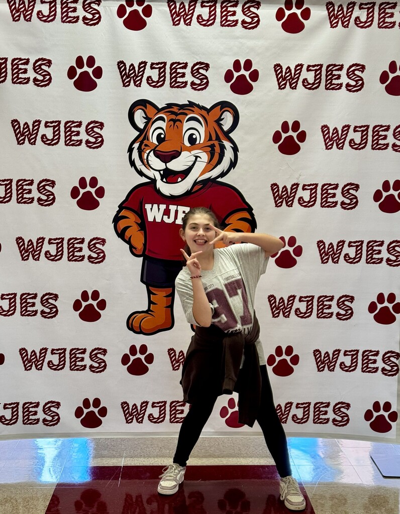 girl standing in front of WJES banner